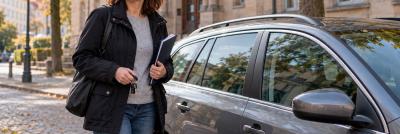 web-Gerichtsvollzieherin-neben-ihrem-privaten-Kombi